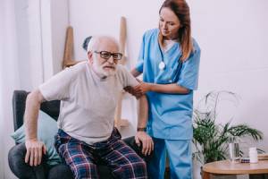 111365451-nurse-helping-old-man-to-stand-up-from-chair